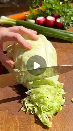 a person cutting up cabbage on top of a wooden table