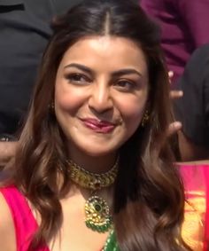 a woman in a pink dress smiling at the camera