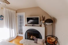 a living room with a fireplace and television on the top shelf, next to a window