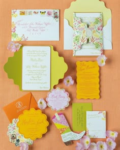 the wedding stationery is laid out on an orange surface with pink flowers and green leaves