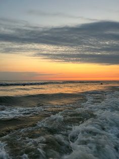 the sun is setting over the ocean with waves