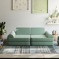 a living room with two green couches and pictures on the wall