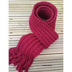 a red knitted scarf sitting on top of a wooden floor