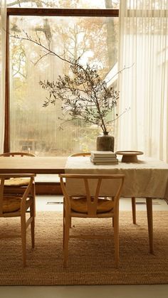 a dining room table with two chairs and a vase on the table next to it