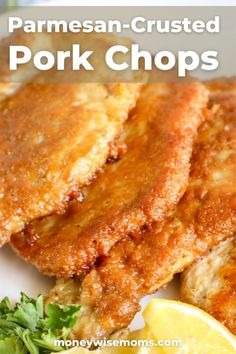 some fried pork chops are on a plate with lemon wedges