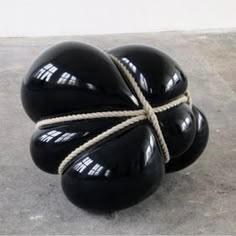 three black balls tied together on concrete