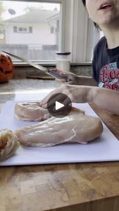 a person cutting up chicken on top of a cutting board