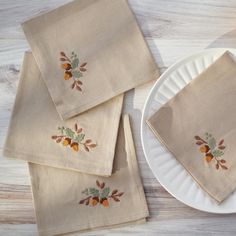 four napkins with embroidered leaves on them