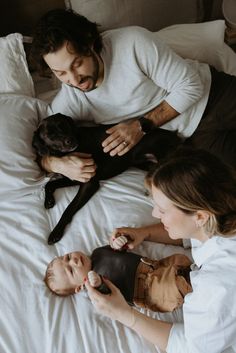 A photo taken from overhead. Mother, father, newborn boy and their small black dog all laying casually on a bed. Toronto Home, Newborn Photoshoot, So Much Love, City Skyline, Feel It