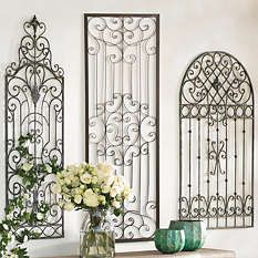 two vases with flowers are sitting on a table in front of three wrought iron wall panels