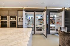 an open refrigerator in a kitchen with marble counter tops and stainless steel appliances on both sides