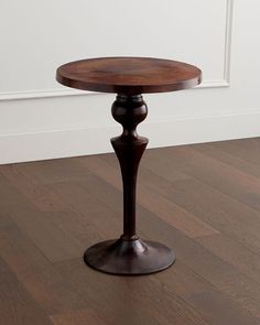 a wooden table sitting on top of a hard wood floor next to a white wall