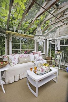 a living room filled with furniture and lots of windows covered in greenery next to a white couch