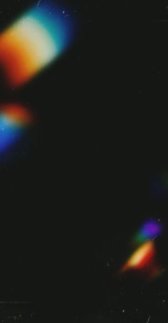 a blurry image of an orange and blue object on a black background with light coming from it