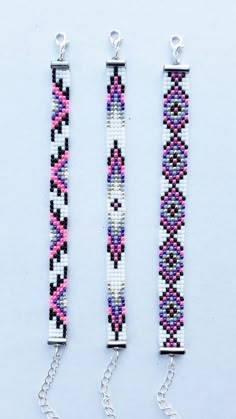 two bracelets made out of beads and chains on a white surface, one is pink and the other is blue