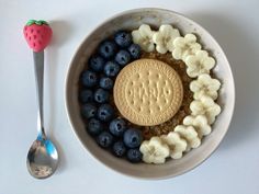 a bowl filled with oatmeal, blueberries and bananas next to a spoon