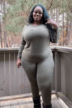 a woman posing on a wooden deck with trees in the background