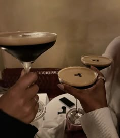 two people holding up martini glasses in front of each other