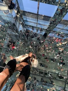 a woman taking a selfie in front of a glass building with lots of people