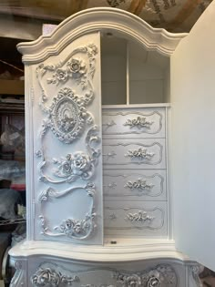 an ornate white armoire with drawers and doors