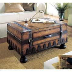 an old trunk coffee table with wine glasses on it and a magazine in the middle