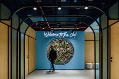 a man is skateboarding in front of a blue wall that reads welcome to the cool