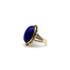 This is part of Chairish’s Fine Jewelry assortment.  A vivid blue lapis cabochon is bezel set into a halo of 22k gold nuggets. The stone is a deep, well-saturated cobalt blue, while the gold nuggets bring richness and texture to the surface of the ring. The effect is stunning, and the two elements compliment each other beautifully. The 14k gold band splits into three, adding a hint of drama and elegantly framing the lapis centrepiece. A bold cocktail ring, true blue!  This type of nugget work ar Yellow Gold Dome Ring With Oval Cabochon Gemstone, 14k Gold Dome Ring With Oval Cabochon, 14k Gold Dome Ring With Oval Cabochon Gemstone, Yellow Gold Oval Cabochon Dome Ring With Gemstone, Oval Lapis Lazuli Rings For Formal Occasions, Classic Yellow Gold Jewelry With Lapis Lazuli, Formal Lapis Lazuli Gemstone Ring, Formal Lapis Lazuli Oval Rings, Blue Domed Jewelry With Polished Finish