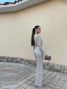 a woman in a silver dress is standing outside