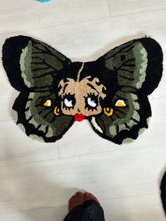 a person standing next to a rug with a large butterfly on it's face