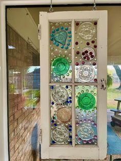 a glass door with many different colored buttons on the front and side panels, hanging from a brick wall