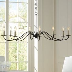 a chandelier hanging from the ceiling in a room with white walls and windows