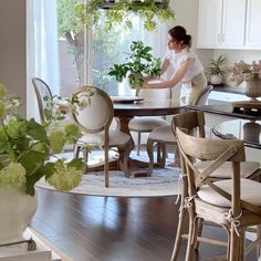 a woman is sitting at a table in the middle of a room with white chairs