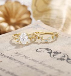 two gold rings sitting on top of a piece of paper next to a vase with flowers