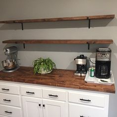 a kitchen with white cabinets and wooden shelves