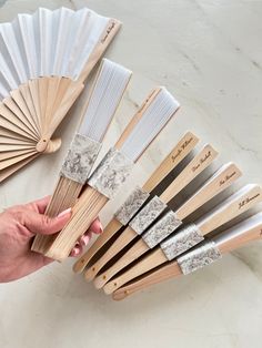 a person holding an assortment of wooden and metal fan