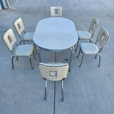 a group of chairs sitting around a table on top of a cement floor next to each other