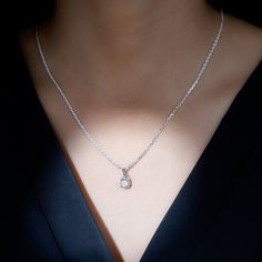 a woman wearing a necklace with a diamond on it