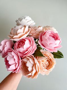 a hand holding a bouquet of pink and white flowers