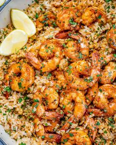 shrimp and rice with lemon wedges on the side in a white bowl, ready to be eaten