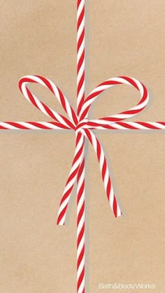 a red and white striped candy cane tied to a brown wrapping paper with a bow on it