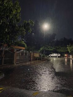 a street at night with cars parked in the rain