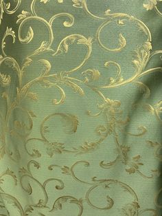 the back side of a green curtain with gold swirls and leaves on it's sides