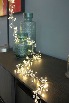 a wooden table topped with a vase filled with flowers and string lights on top of it