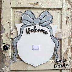 a welcome sign hanging on the side of a door with a bow and ribbon around it