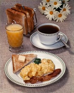 a breakfast plate with toast, eggs and bacon on it next to a glass of orange juice