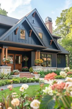 a blue house with lots of flowers in the front yard and landscaping on either side