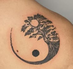 a tattoo on the back of a man's shoulder with a tree and moon