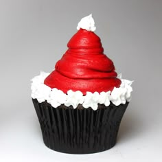 a red cupcake with white frosting and a santa hat on top