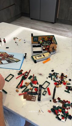 a man sitting at a kitchen table with legos all over the counter and in front of him