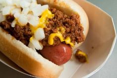 a chili dog with mustard and onions on a plate